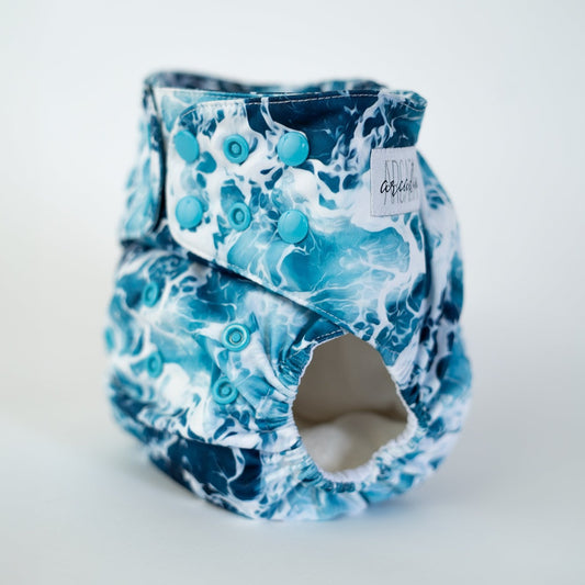 A photo of a cloth diaper in the print Sea Foam, which is a captivating high contrast water/sea pattern. Front angle view.