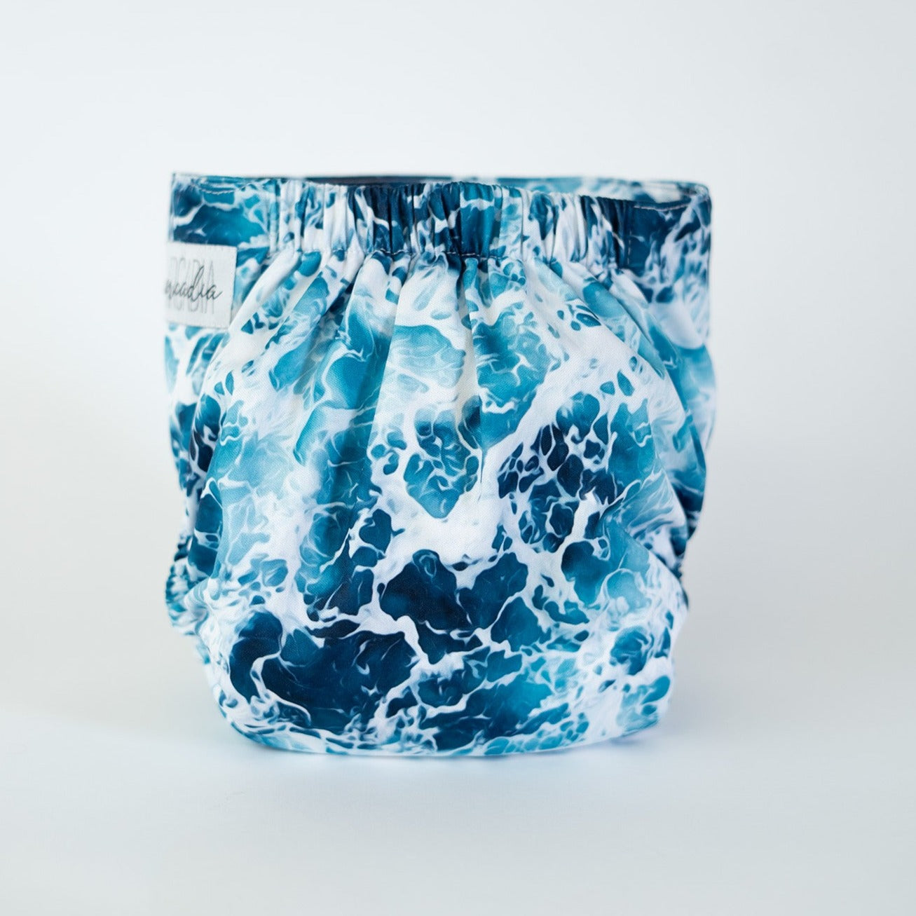 A photo of a cloth diaper in the print Sea Foam, which is a captivating high contrast water/sea pattern. Rear view.