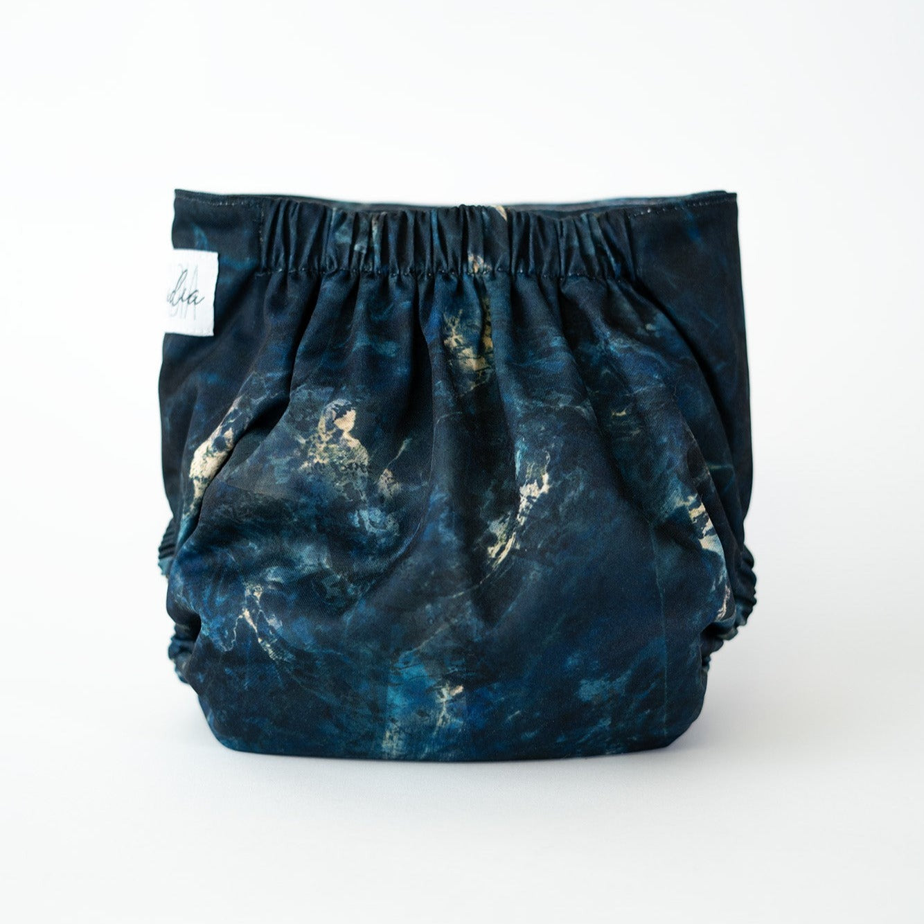 The back view of a pocket style cloth diaper in the Apatite print, photographed against a clean white background. The design is a deep blue stone look print, featuring gold veins that bleed into one another organically. The gathered elastic waistband creates a comfortable, secure fit.