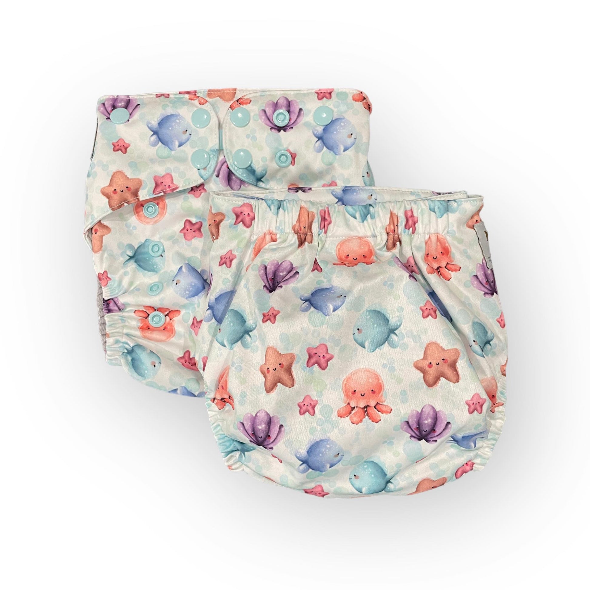 a photo showing 2 of the same print pocket cloth diaper. The print background is white with light blue bubbles. The illustrations on the diapers are cute cartoony watercolor ocean critters like sea stars, clams, octopus, and fish.