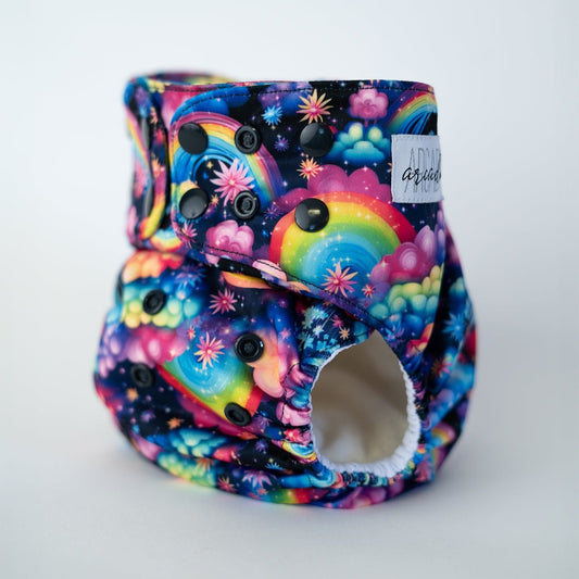 A cloth diaper with a vibrant retro rainbow, flower, and cloud print. The colors are neon and high contrast.