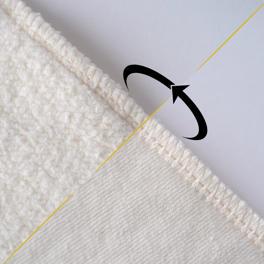 Close-up of a textured white fabric with gold lines and a black arrow indicating the reversable nature.