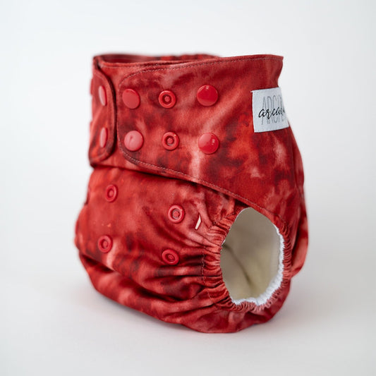 A vibrant cloth diaper in a monotone red watercolor pattern, perfect for adding a bold touch to your baby's diaper collection. Front angle view.