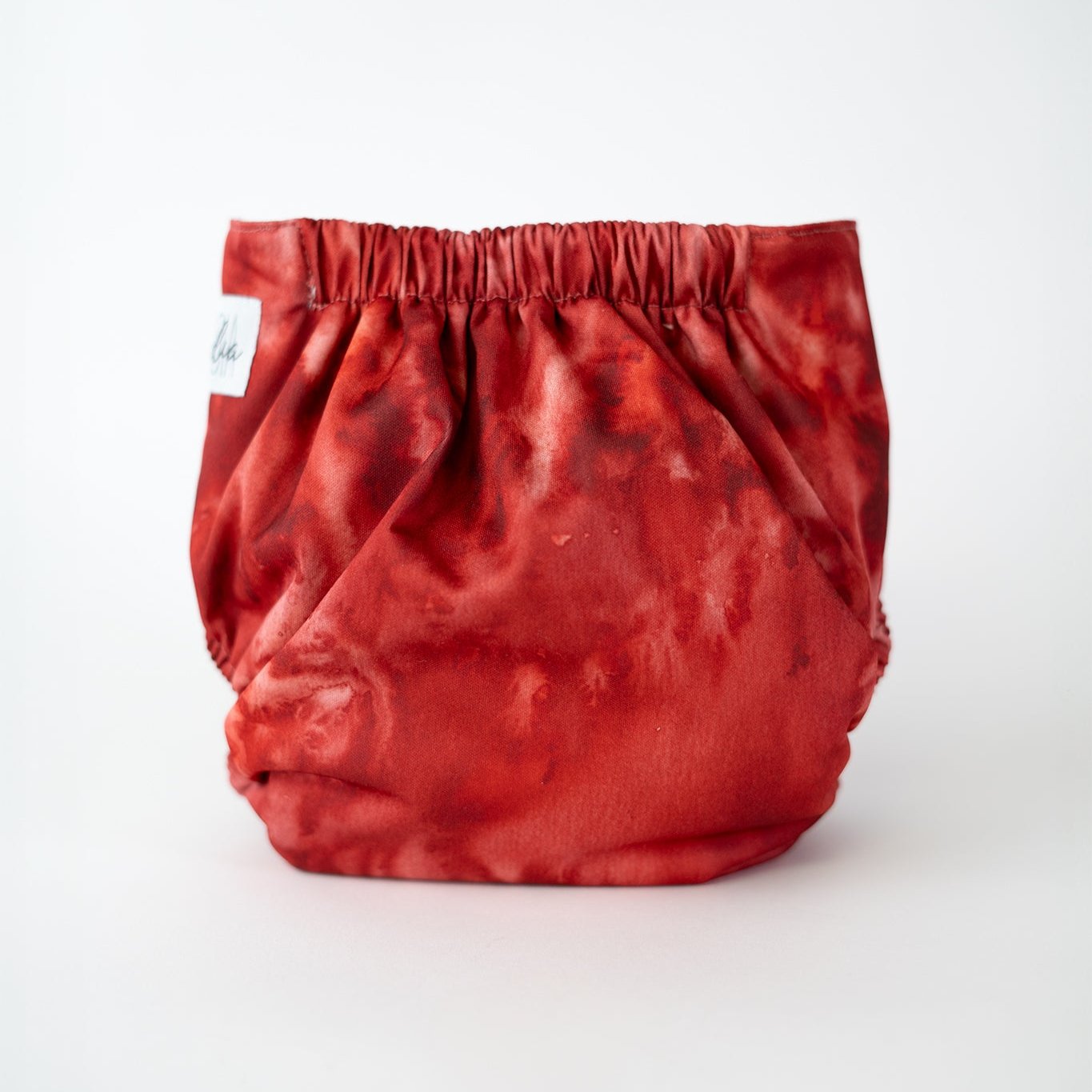 A vibrant cloth diaper in a rich red and orange tie-dye pattern, perfect for adding a bold touch to your baby's diaper collection. Rear view.