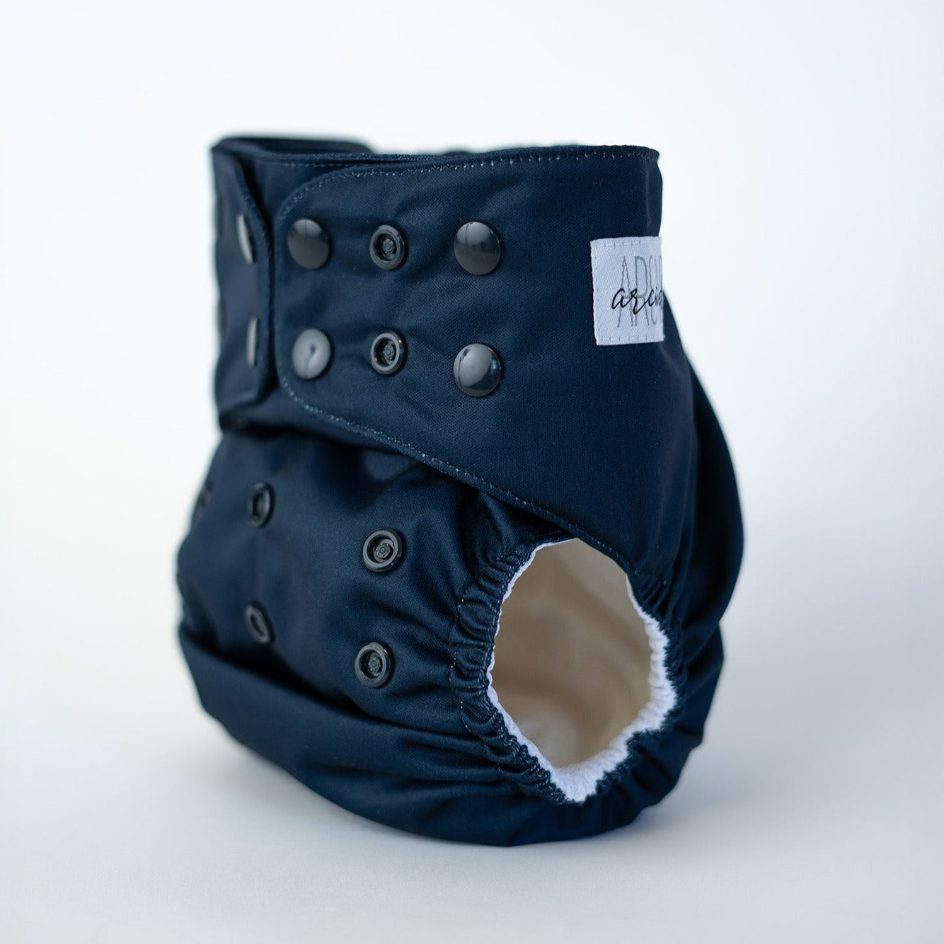 A navy-colored pocket diaper with snap buttons and a visible arcadia's nursery label.
