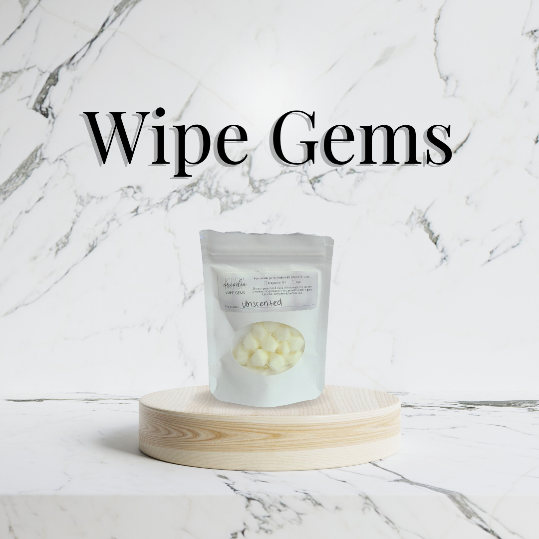 A pack of cloth wipe bits on a wooden pedestal, on a marble countertop with a marble background. Serif text at the top reads "Wipe Gems"