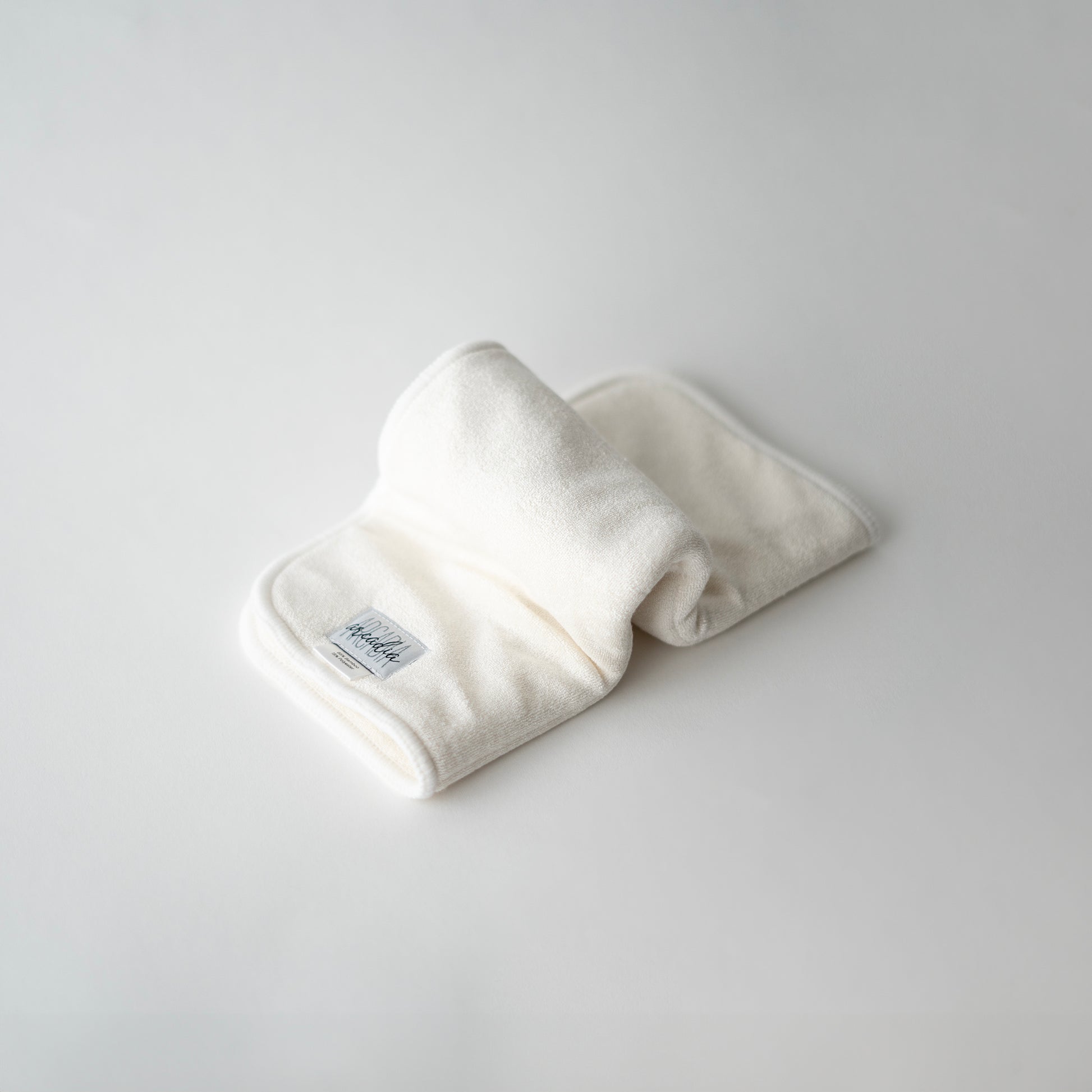 A folded bamboo terry doubler insert for cloth diapers, displayed on a white background, in an inchworm formation.