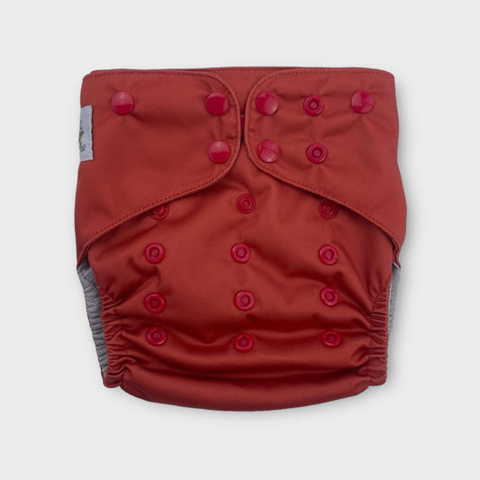 a wickham wild reusable pocket style diaper. The color is a solid scarlet, a deep reddish orange. the snaps are a deep red.