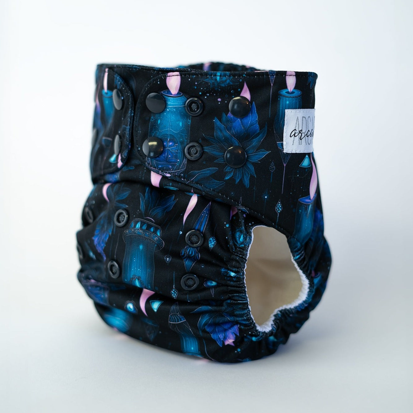 A witchy candle patterned pocket diaper with adjustable snap buttons and a elasticized back panel.
