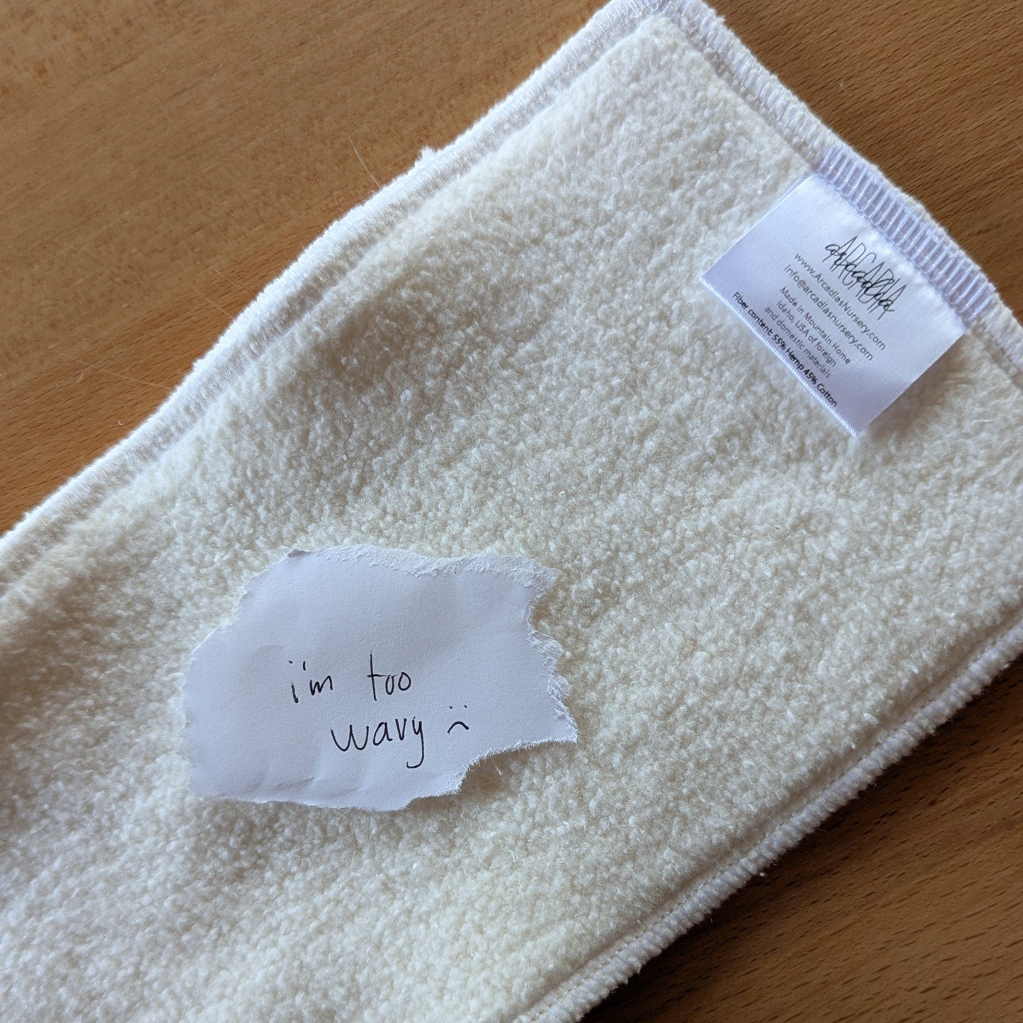 A photo of a seconds quality hemp cotton insert with a paper note on top that reads "I'm too wavy :("