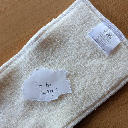 A photo of a seconds quality hemp cotton insert with a paper note on top that reads "I'm too wavy :("