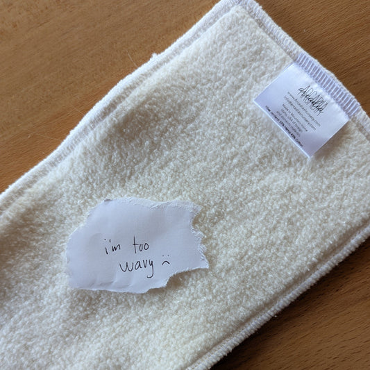 A photo of a seconds quality hemp cotton insert with a paper note on top that reads "I'm too wavy :("