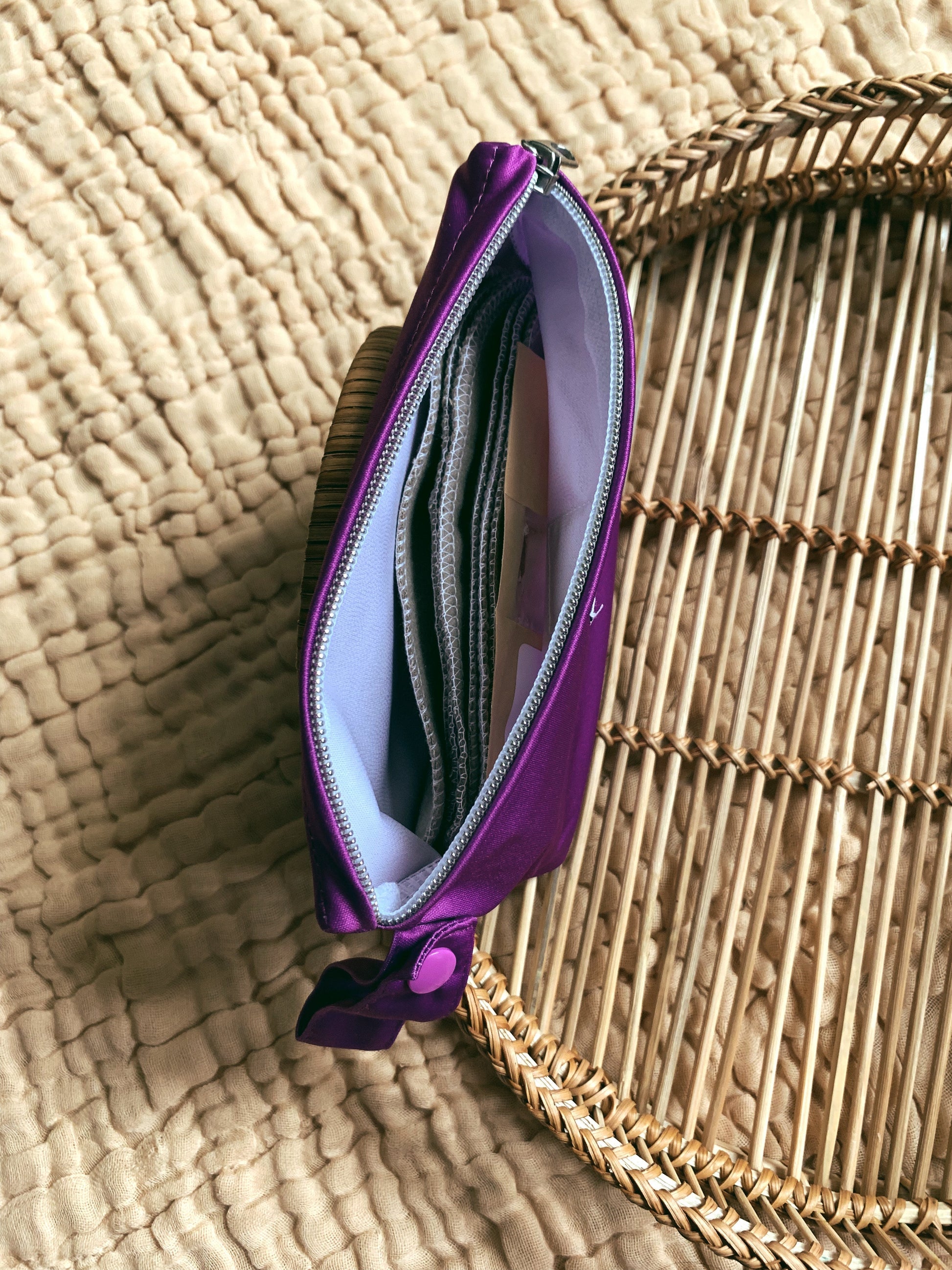 a purple andiamo pouch witht he zipper open from the top showing the size. inside is a wipe bit pouch and cloth wipes.